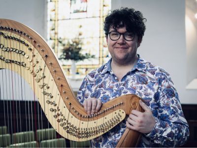 Alex Rider holding a harp smiling
